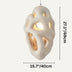 White sculptural pendant light with organic cutout design and warm interior glow, hanging against neutral background.