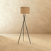 Tripod floor lamp with cylindrical shade, black metal frame, white background, front view