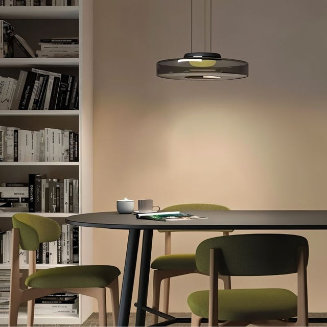 "A glass disc pendant light above a dining table in a modern dining room."