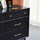 "Gold brass knobs and pull bars with cylindrical design, mounted on a black wooden dresser with drawers."