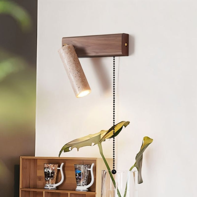 "Lindr bedside wall lamp in a reading corner, crafted from travertine and walnut, with a pull chain for easy light control."