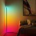 Modern linear floor lamp with black metal finish casting vibrant gradient light from cyan to magenta against a living room wall.