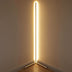 Tall linear floor lamp with white neon tube and gold base positioned in room corner against beige walls.