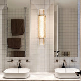 "Modern crystal wall lamp with a vertical, cylindrical design, mounted on a wall in a contemporary bathroom."