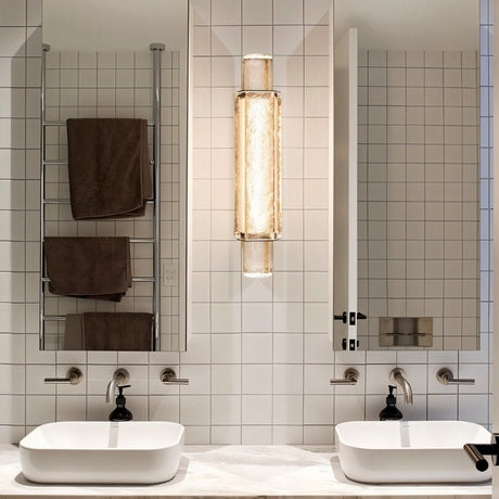 "Modern crystal wall lamp with a vertical, cylindrical design, mounted on a wall in a contemporary bathroom."
