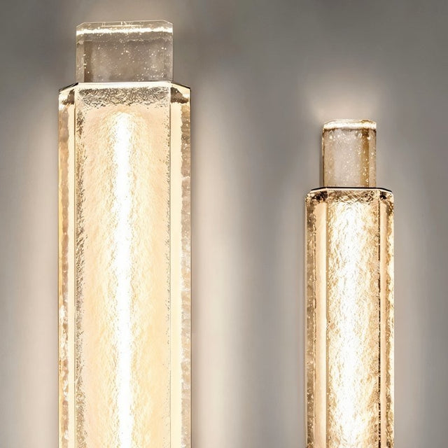 "Pair of modern crystal wall lamps with a vertical, cylindrical design, emitting a soft, diffused light."