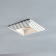 "Recessed square downlight made from gypsum and aluminum with ribbed edges, offering focused, glare-free illumination in modern kitchens, living rooms, and offices."