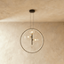 Modern pendant light with black metal frame, clear glass spheres, and brass accents, displayed above dining table in contempo