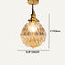 Brass pendant light with amber geometric glass shade hanging against white background.