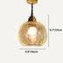 Brass pendant light with textured amber glass globe shade shown against neutral background.