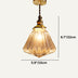 Amber glass pendant light with brass hardware suspended against a white background.