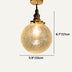 Amber glass globe pendant light with brass fixture and vintage-style socket on white background.