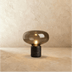 Gold mushroom-shaped table lamp with black marble base on nightstand, lifestyle bedroom setting