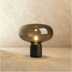 Amber glass dome table lamp with black marble base on wooden surface, white studio background