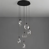 "Pendant lights with uniquely shaped crystal droplets hang from a round, black canopy against a grey background."
