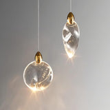 "Close-up of two uniquely shaped crystal pendant lights with gold accents, showcasing their elegant design and warm glow."