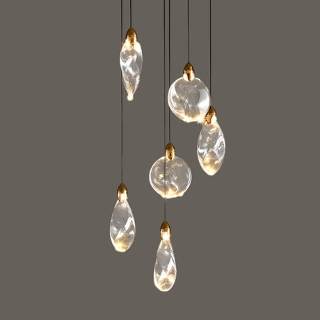 "A collection of uniquely shaped crystal pendant lights with gold caps hang against a grey background, showcasing their elegant design and warm illumination."