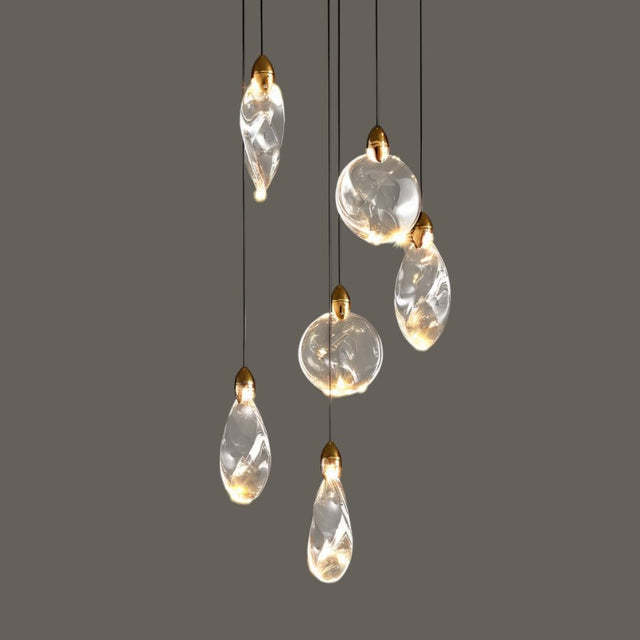 "A collection of uniquely shaped crystal pendant lights with gold caps hang against a grey background, showcasing their elegant design and warm illumination."