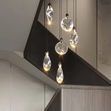 "A cluster of uniquely shaped crystal pendant lights hang above a modern staircase, creating a cascading effect of warm light."