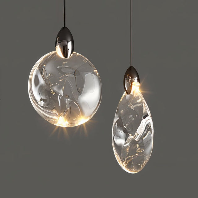 "Two uniquely shaped crystal pendant lights, one round and one teardrop, hang against a grey background, showcasing their elegant, modern design and warm light."