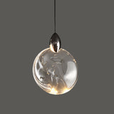 "A round, crystal pendant light with a metallic cap hangs against a grey background, showcasing its modern design."
