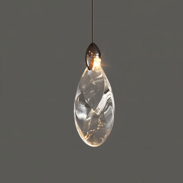 "A single, teardrop-shaped crystal pendant light with a dark metallic top, casting a warm glow against a grey background."