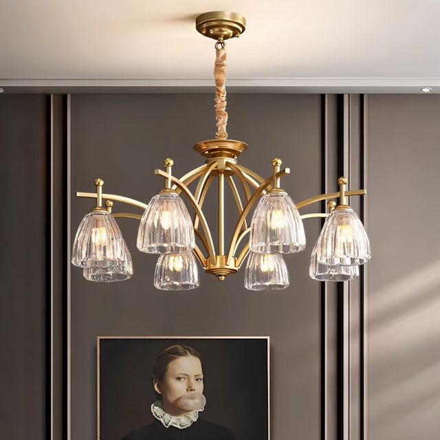 "Gold chandelier with six glass shades hanging over a living room with artwork."