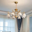 "Close-up of a gold chandelier with eight glass shades hanging over a dining room table."
