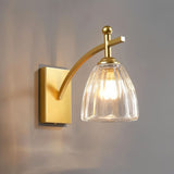 "A brushed gold wall lamp with a fluted glass shade."