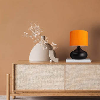 "Lumir table lamp with ceramic base and fabric shade on a console table in a modern living room."