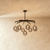Multi-tier brass chandelier with seven clear glass globe pendants in modern living room setting with sofa and plants.