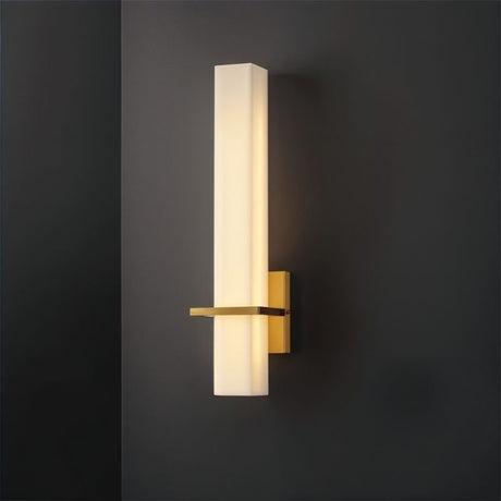 "Modern wall lamp with an alabaster shade and brass accents, mounted on a dark wall, providing soft ambient lighting"