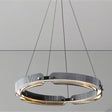 "A close-up view of a modern, circular chandelier with a segmented ring design, made of iron and glass, suspended by thin cables."