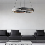 "A modern, circular chandelier with a segmented ring design, made of iron and glass, suspended by thin cables in a minimalist living space."