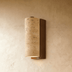 "Two travertine wall lamps with cylindrical shades and wooden bases, illuminating a hallway with a patterned floor and a dark wood door."