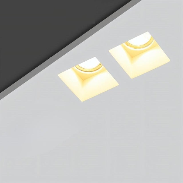 "Pair of trimless recessed downlights made from gypsum and aluminum, seamlessly installed in a modern ceiling, providing efficient and focused lighting for contemporary spaces."