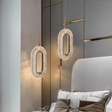 Modern Luxin Pendant Light with sculptural oval design in copper and acrylic, suspended beside a contemporary upholstered bed.