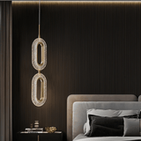 Double Luxin Pendant Light in copper and acrylic, casting soft ambient glow in a dark-toned modern bedroom with vertical paneling.