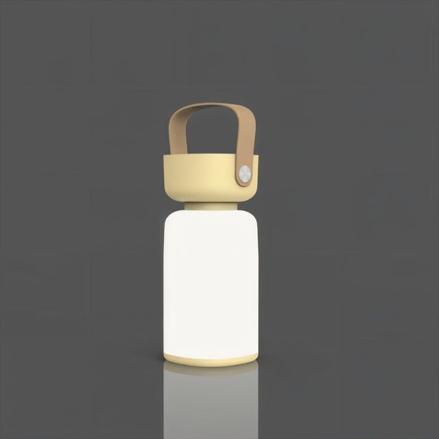 "A beige and white cylindrical table lamp with a handle, lit up against a dark gray background."