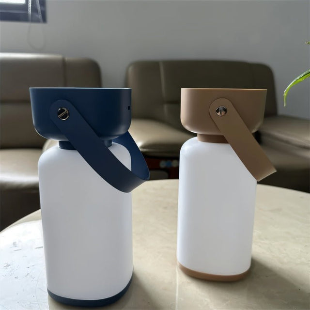 "Two cylindrical table lamps with handles, one in blue and white, the other in beige and white, sitting on a table."