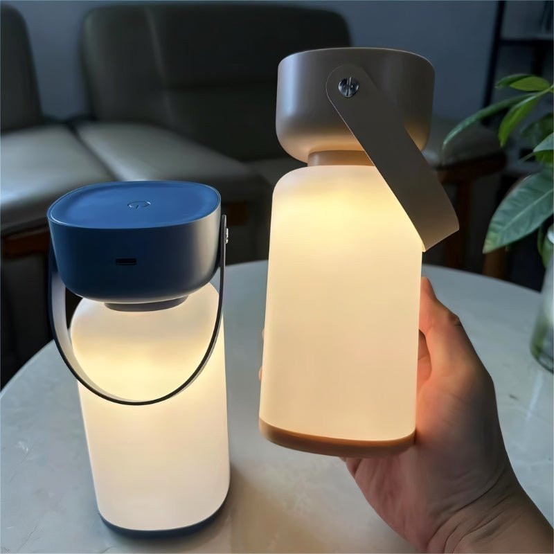 "Two cylindrical table lamps with handles, one in blue and white, the other in beige and white, being held by a hand."