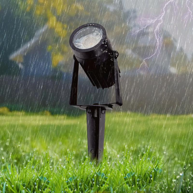 "Weatherproof outdoor spotlight in a garden during a rainstorm with lightning."