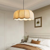 "Mashi pendant light with a fabric shade hanging in a bedroom above a bed."