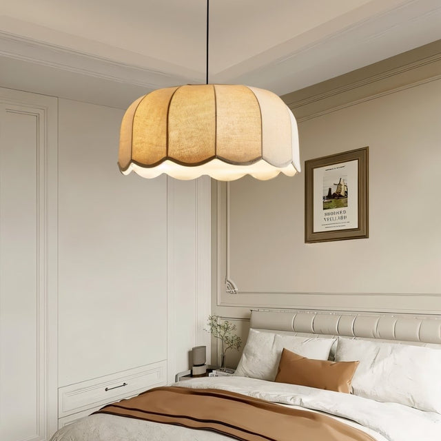 "Mashi pendant light with a fabric shade hanging in a bedroom above a bed."
