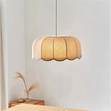 "Mashi pendant light with a fabric shade hanging in a bedroom, with a wooden dresser and decorative grasses."