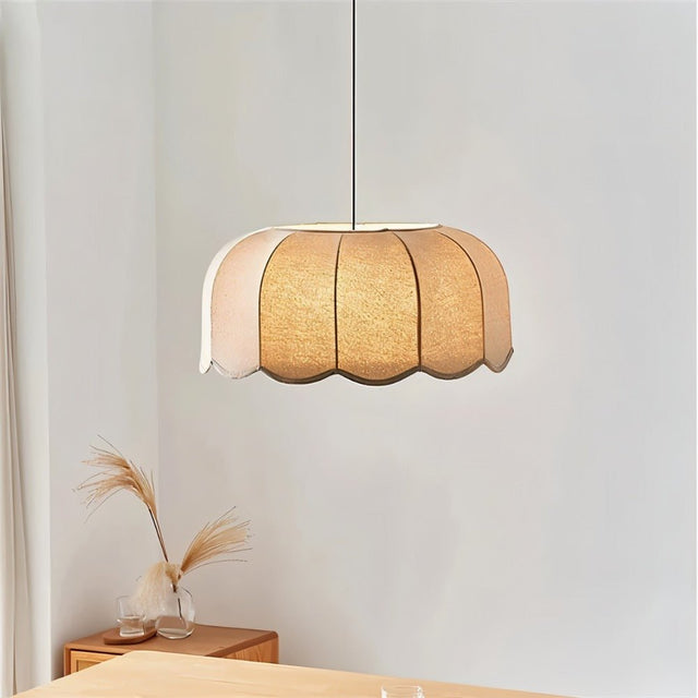 "Mashi pendant light with a fabric shade hanging in a bedroom, with a wooden dresser and decorative grasses."