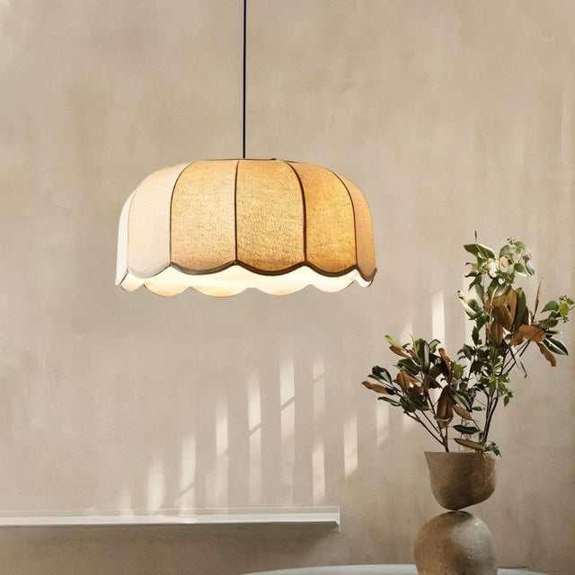 "Mashi pendant light with a fabric shade hanging in a dining room, with a plant in a pot on a table."