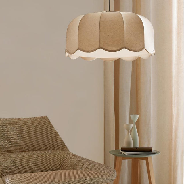 "Mashi pendant light with a fabric shade hanging in a living room, with a beige armchair and a small side table."