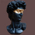 Black resin bust sculpture of David with gold-accented eye mask against neutral background.
