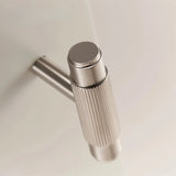 "Close-up of a modern brass knurled cabinet knob on a white surface."